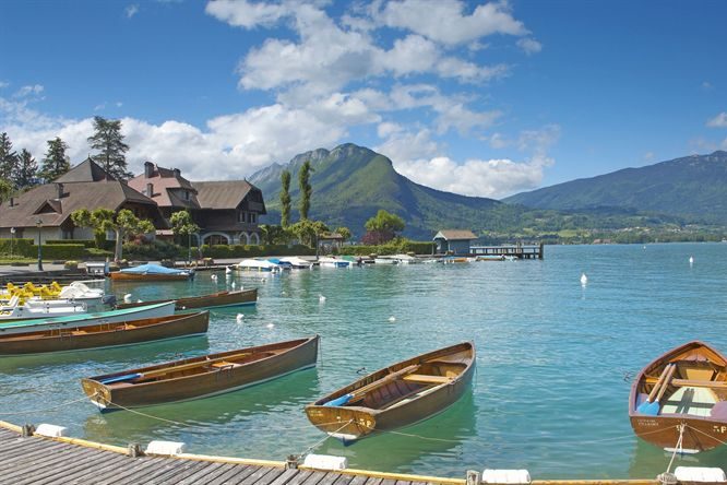 Circuit touristique Classe-Affaires VTC Paysage alpin verdoyant avec un village pittoresque et des montagnes en arrière-plan.