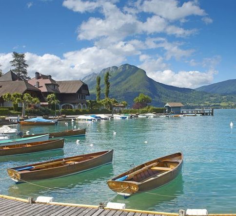Canaux pittoresques d'Annecy, avec bâtiments colorés et montagnes en arrière-plan.