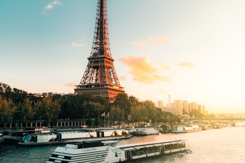 Classe-Affaires VTC Chamonix Mont-Blanc - Archamps - Paris Tour Eiffel au coucher du soleil, avec des péniches sur la Seine en premier plan.