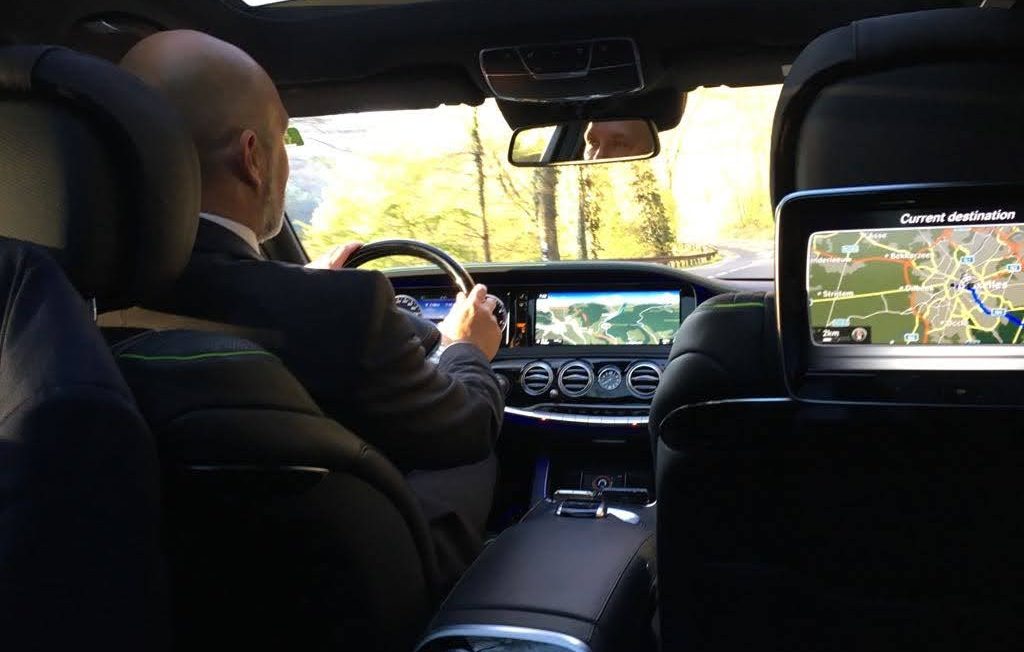 Classe-Affaires VTC - Chamonix - Chauffeur Privé A driver's hand holding the steering wheel, seen through the blurred windshield.