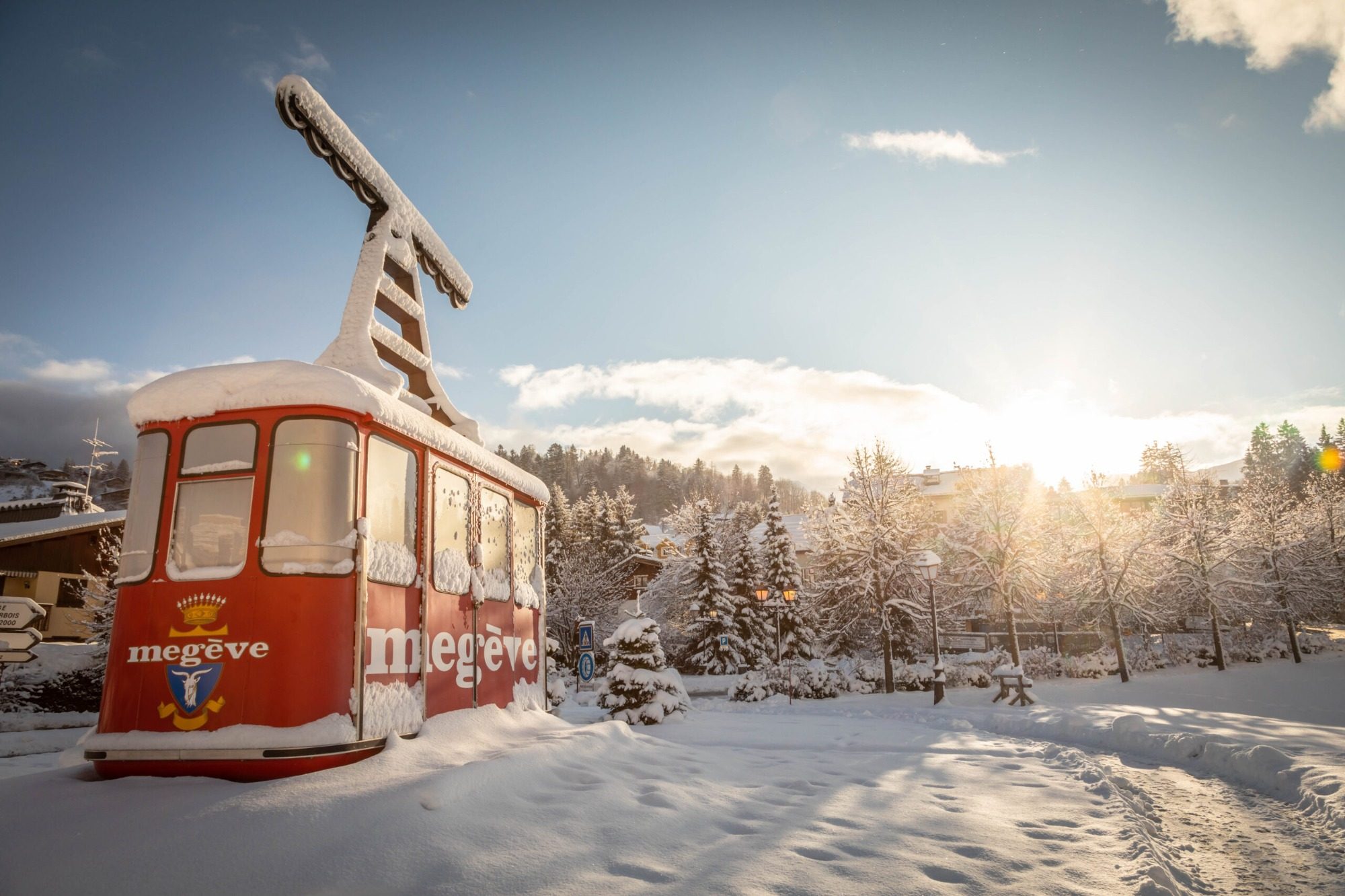 Classe-Affaires VTC Megève Val d'Arly Cabine de téléphérique rouge à Megève entourée de neige, au coucher du soleil.