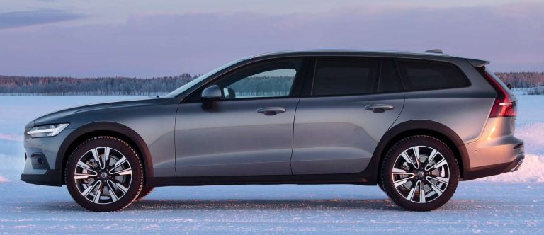 Voiture de tourisme grise sur un terrain enneigé, vue de profil.