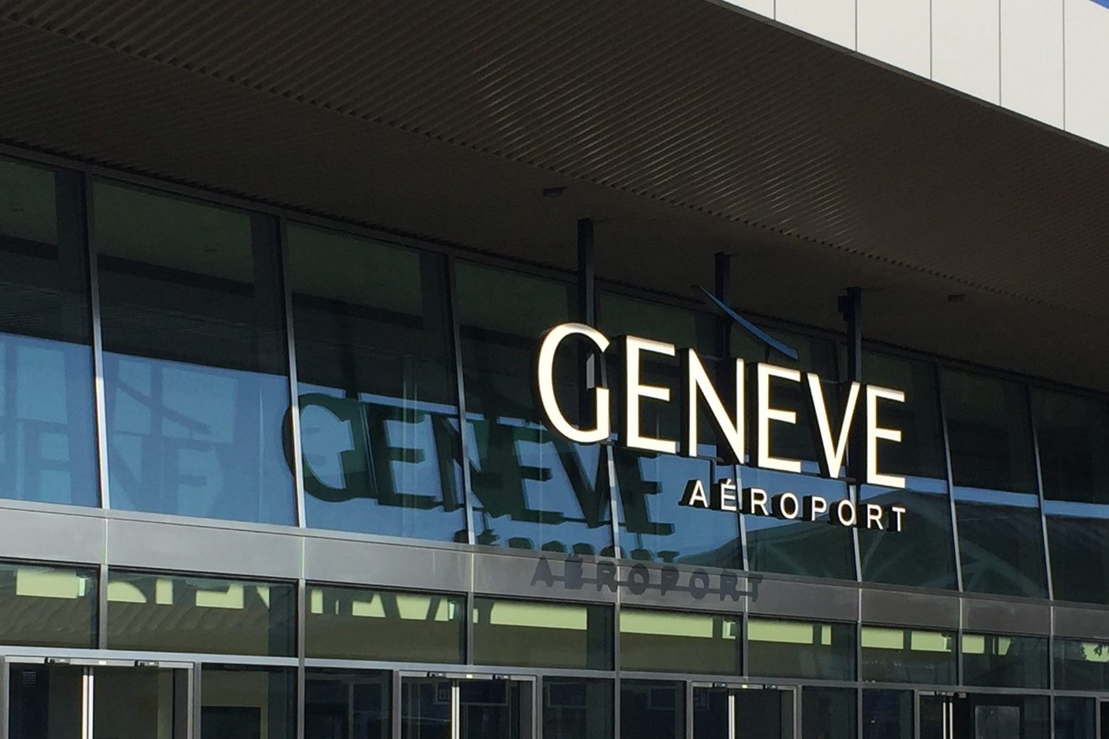 Classe-Affaires VTC Genève International Airport Texte affiché "GENEVE AÉROPORT" sur la façade d'un bâtiment moderne.