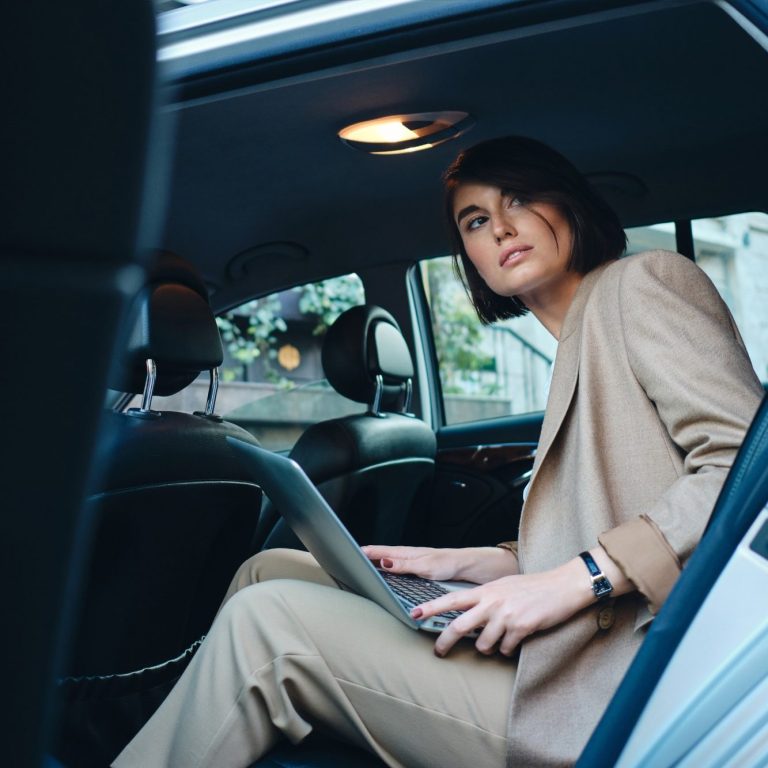 Volvo V60 Classe-Affaires VTC Haute-Savoie Femme assise à l'arrière d'une voiture, utilisant un ordinateur portable.